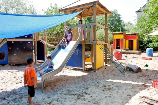 Auf unserem Außengelände befindet sich neben einer großzügigen Sandfläche und Gebüschen, in denen die Kinder spielen und sich verstecken können, eine große Spiel - und Kletterlandschaft. 