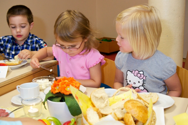 Die Kinder frühstücken an einem ansprechend gedecktem Frühstückstisch in gemütlicher
Runde.