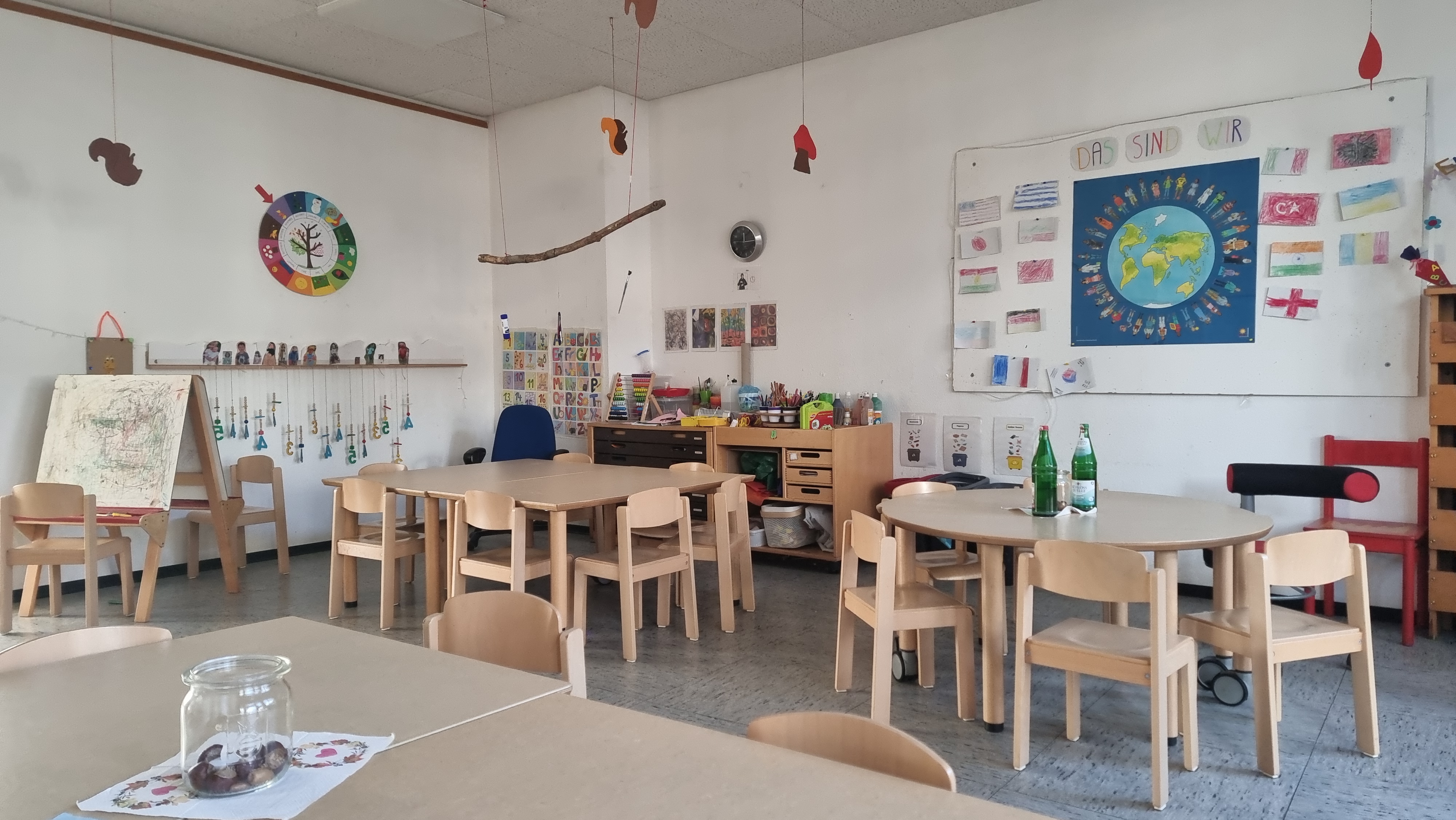 Zu sehen ist ein Gruppenraum der 1.Etage mit einem Kreativbereich und verschiedenen Tischen. Die Tische werden für den Kreativbereich, wie auch für Spiele und Puzzles und für die Mahlzeiten g