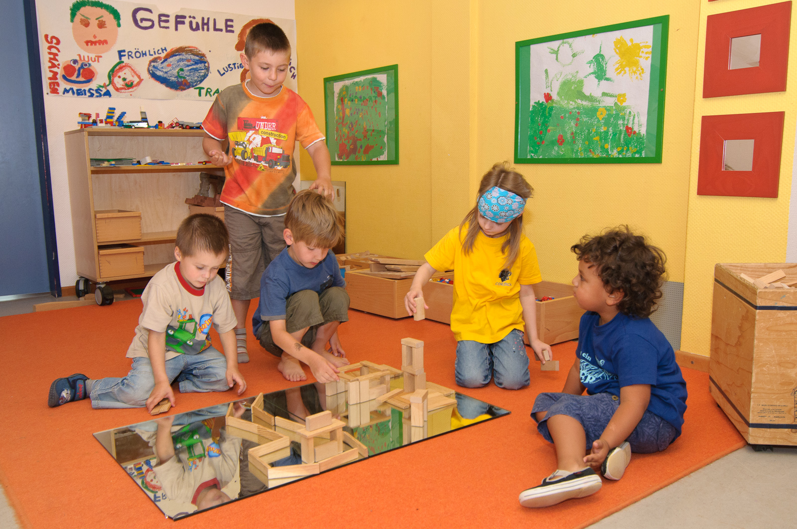 Kinder bauen mit Bauklötzen auf einem Spiegel.