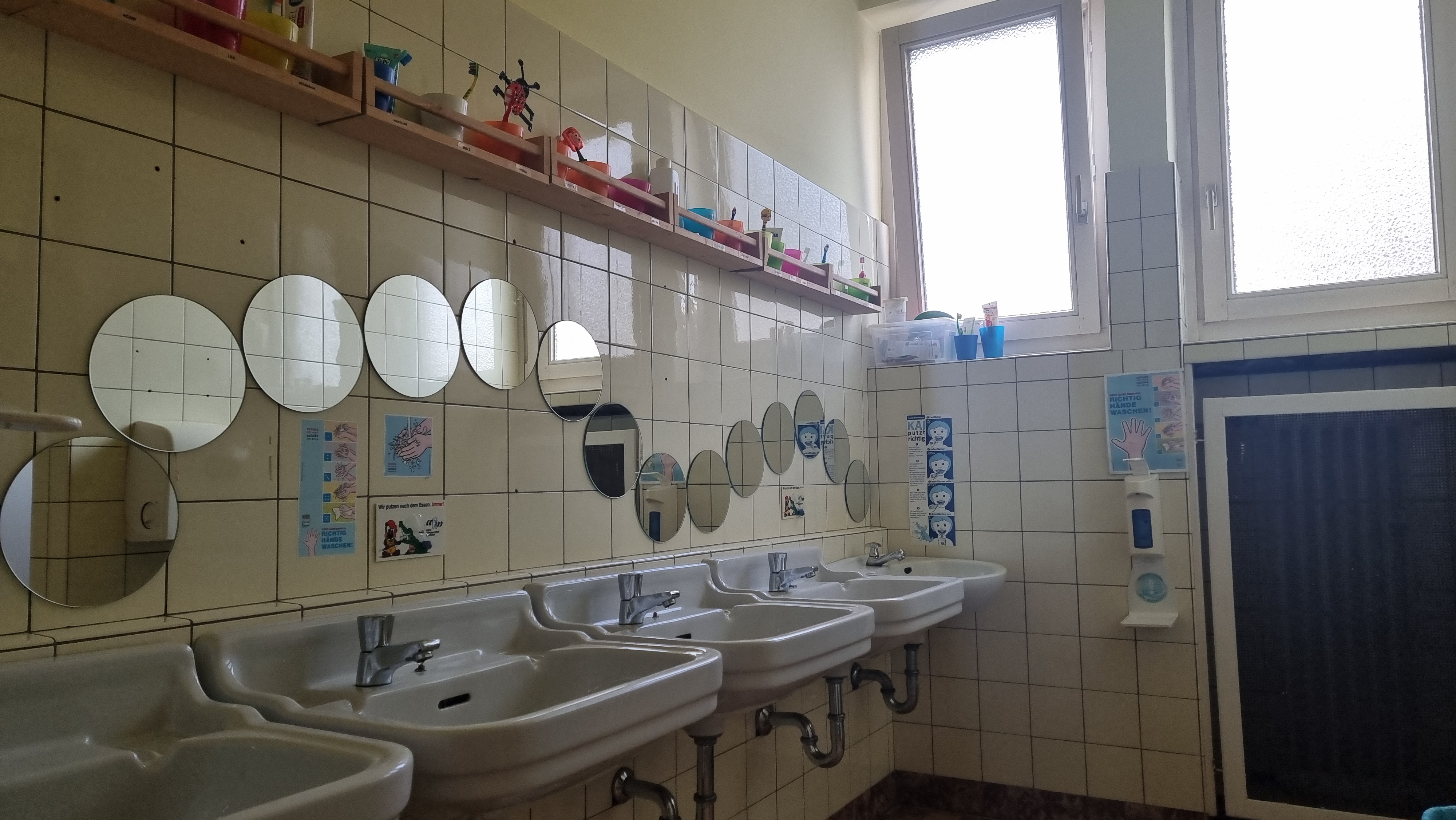 Auf diesem Foto ist einer unserer Waschräume für die Kinder zusehen.  Es gibt mehrere Waschbecken mit Spiegeln für die Kinder.