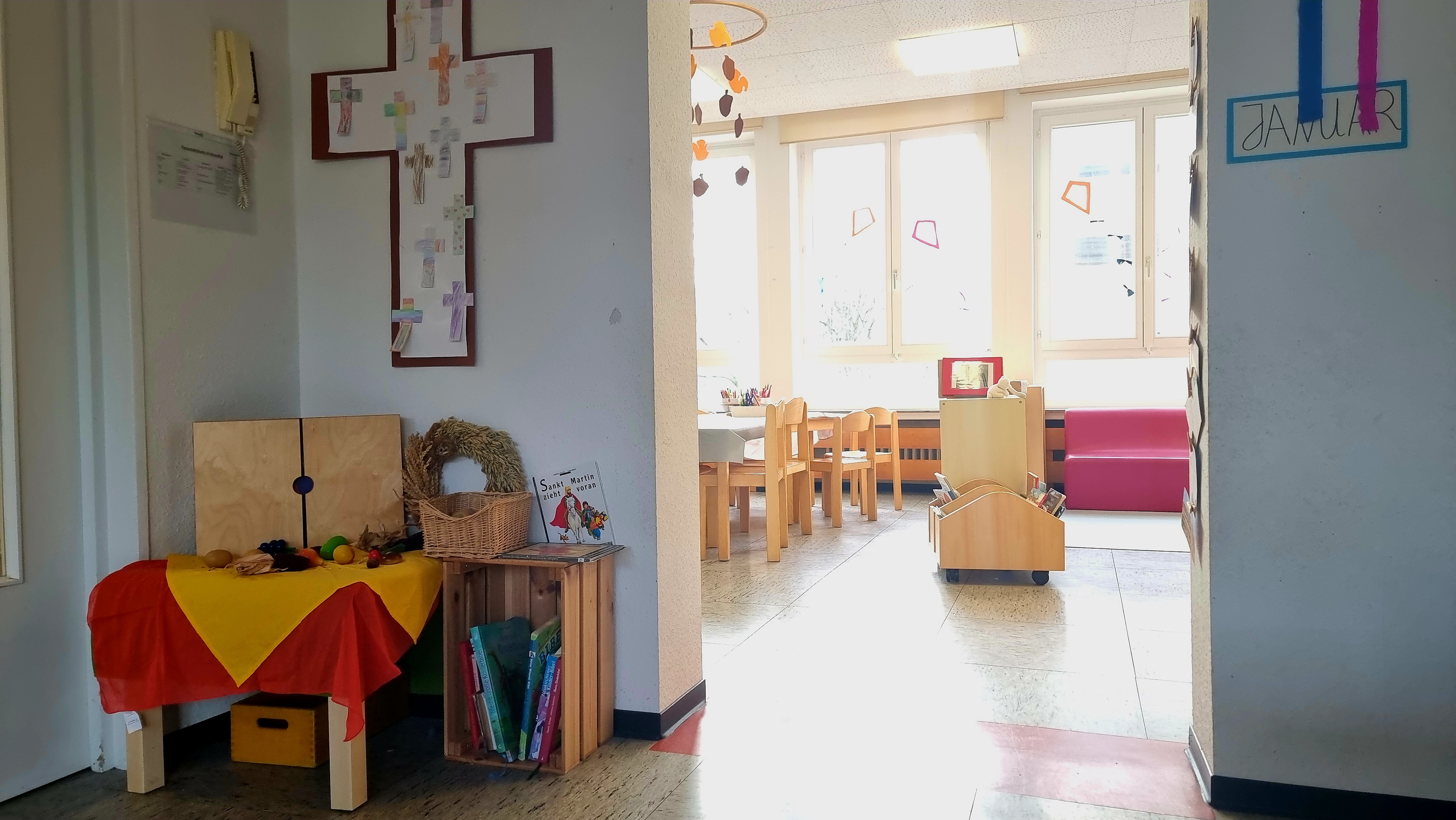 Hier ist der Blick von einem in den anderen Gruppenraum zu sehen. Im Vordergrund des Bildes ist unsere religionspädagogische Ecke mit ein Tisch zum Thema Erntedank  und verschiedene religions